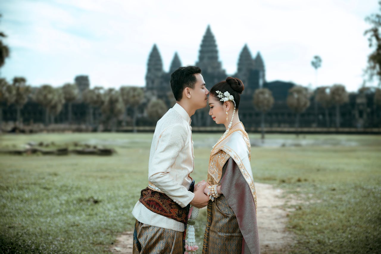 A couple in traditional Cambodian attire embracing at Angkor Wat, a symbol of timeless love.