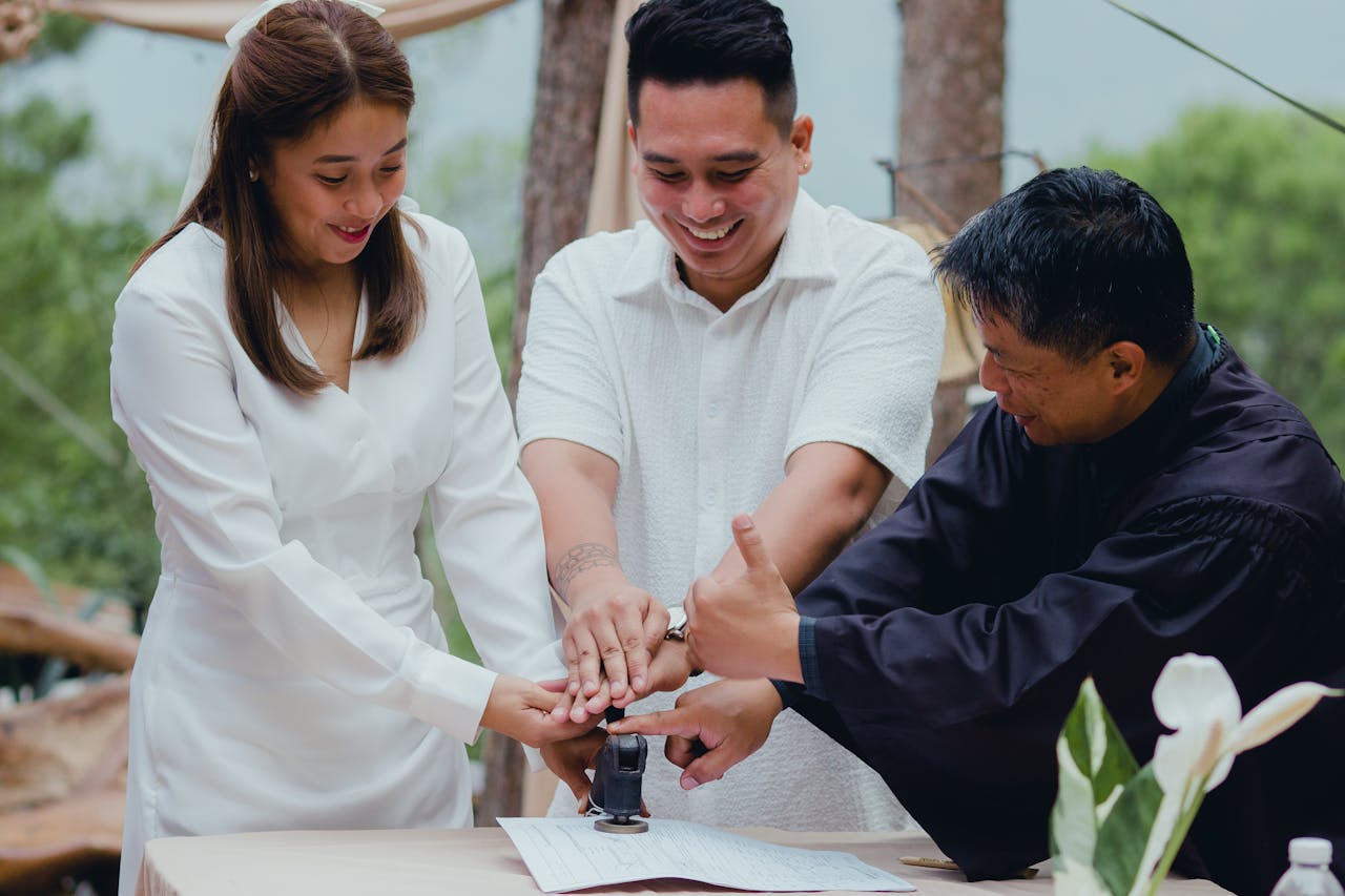 A joyful couple finalizing their wedding with the officiant outdoors.