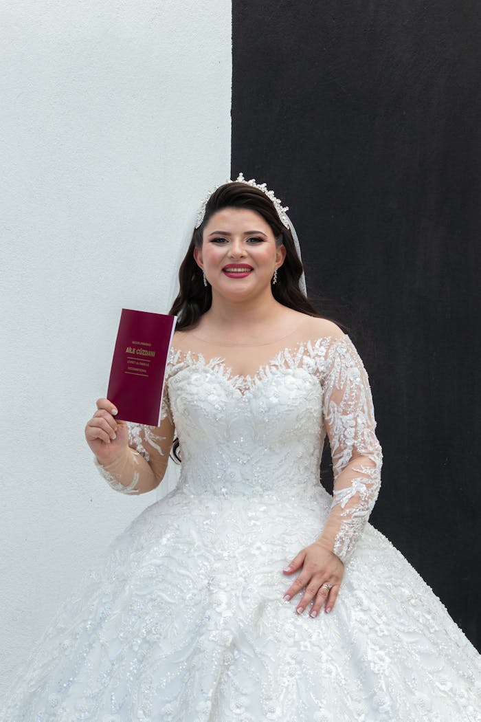 Bride in elegant gown smiling and holding a wedding certificate in Ödemiş, İzmir.