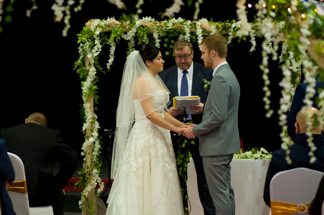 Bride and groom exchanging vows under a picturesque floral arch during a wedding ceremony.
